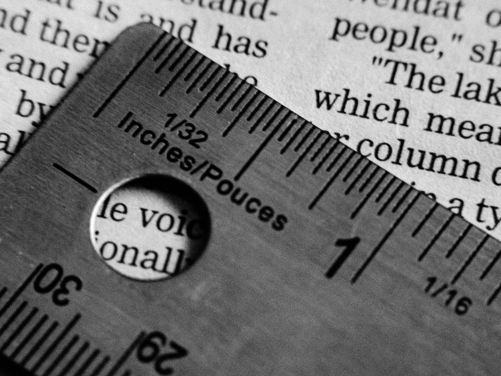 Règle métallique marquée en pouces, en français et en anglais, sur un texte imprimé