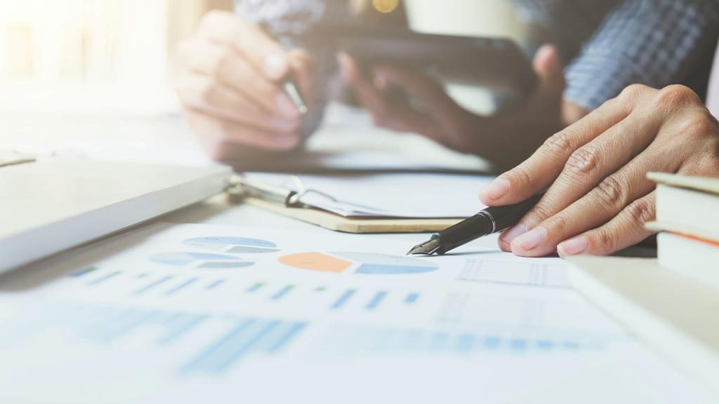 Person reviewing charts and financial statements with a pen